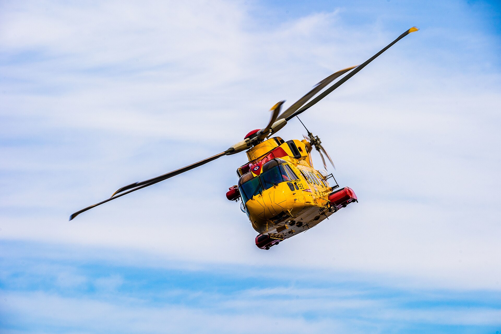 A yellow CH-149 Cormorant search-and-rescue helicopter hovering over the sea