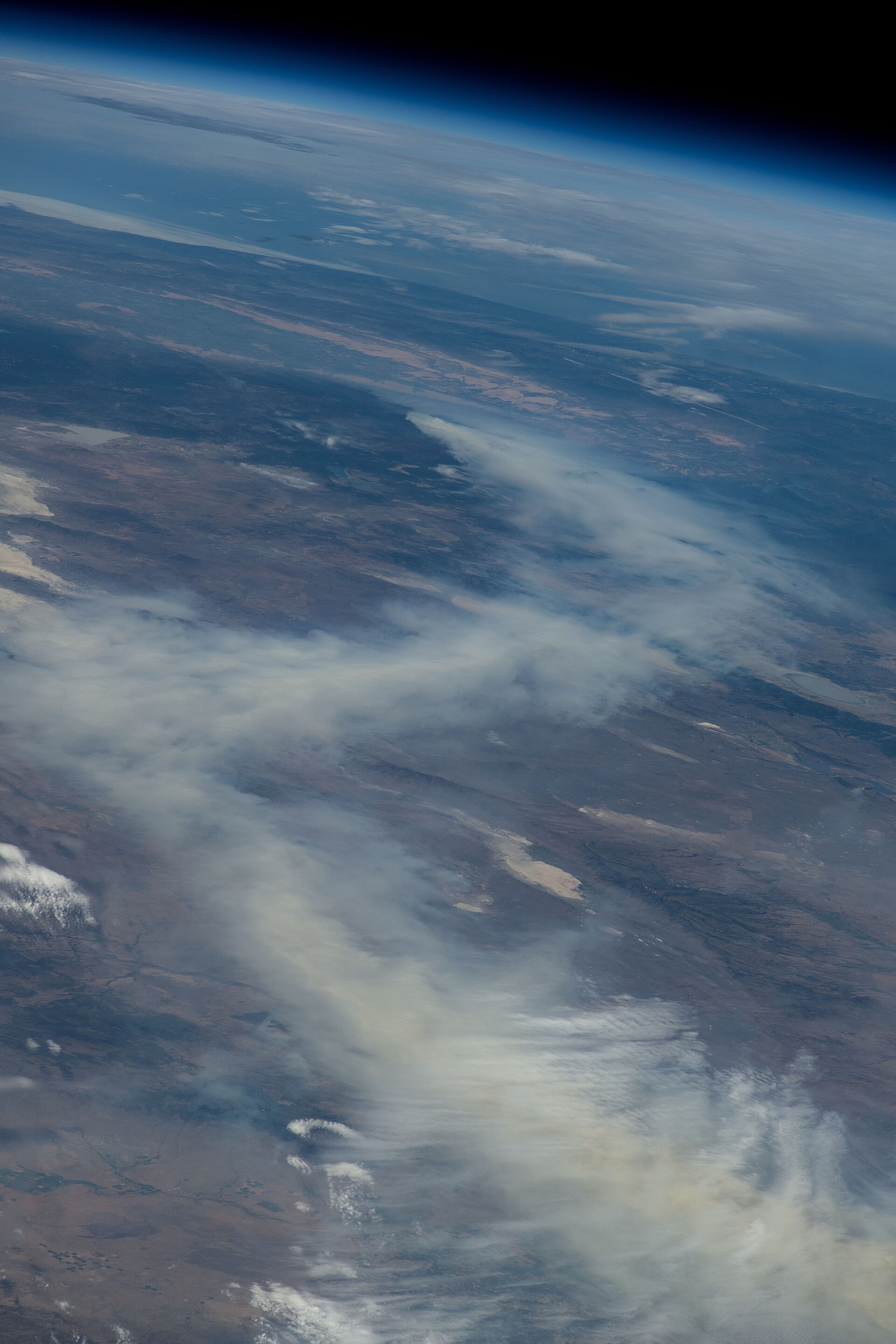 A column of wildfire smoke rising over Canadian forest, photographed from orbit
